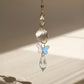 Attrape-lumière décoratif avec papillon, cristal suspendu créant une ambiance poétique grâce aux jeux de lumière du soleil.