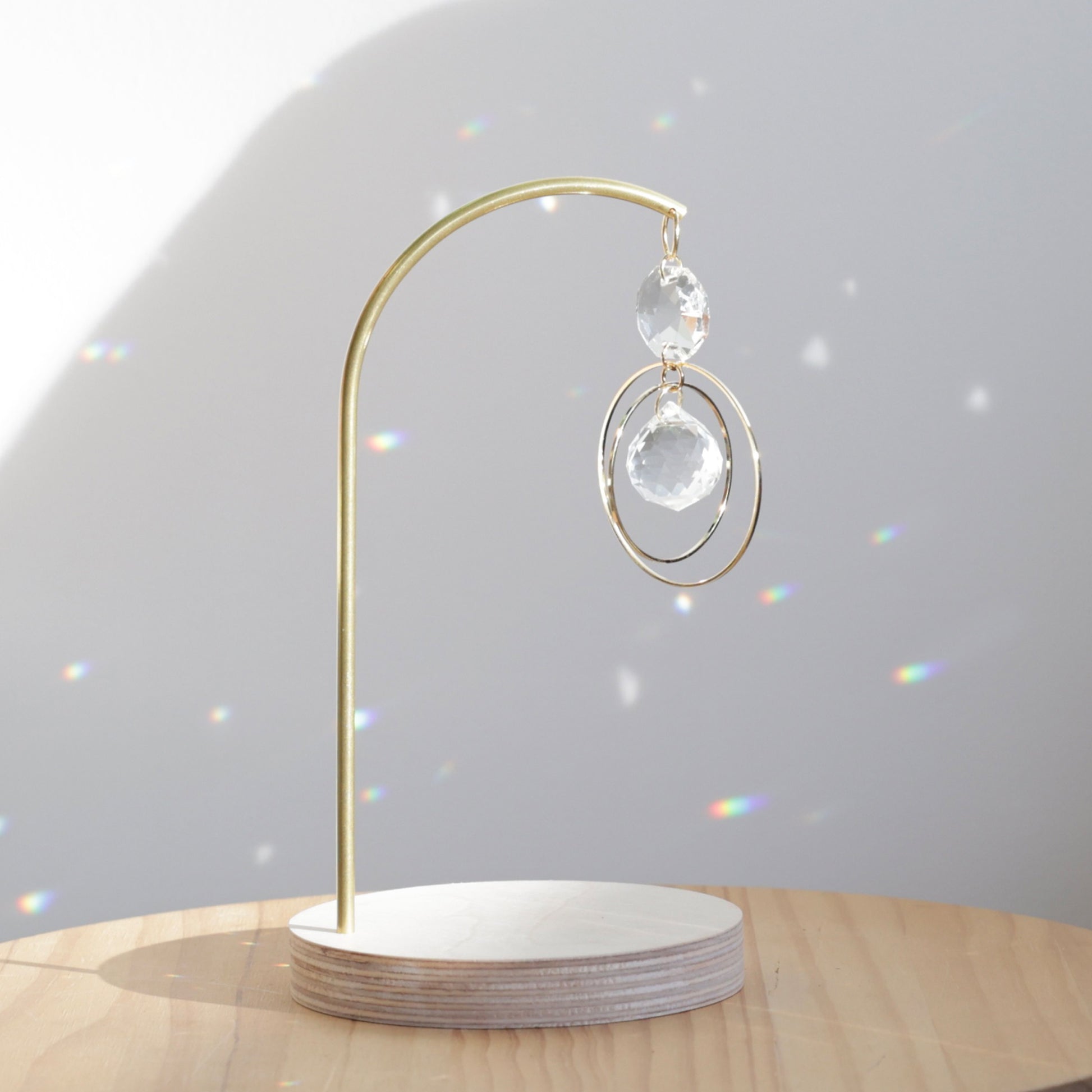 Suncatcher DAYDREAM sur pied avec base ronde en bois naturel, illuminé par la lumière du soleil, de la marque Rayonne®