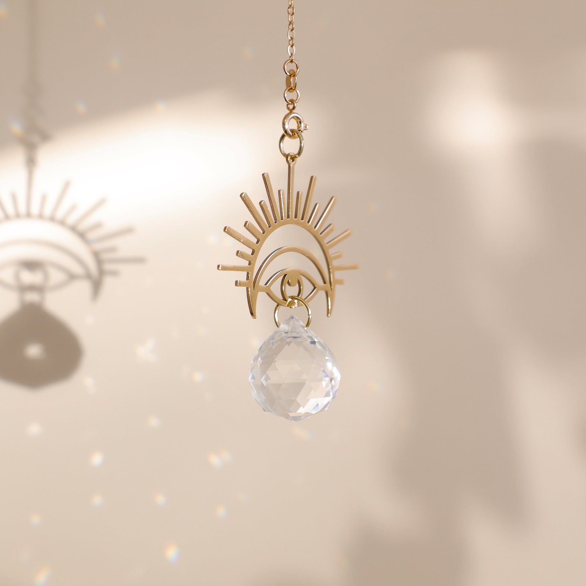 Suncatcher WONDER avec cristal et apprêt en forme d’œil, projetant de magnifiques reflets arc-en-ciel.