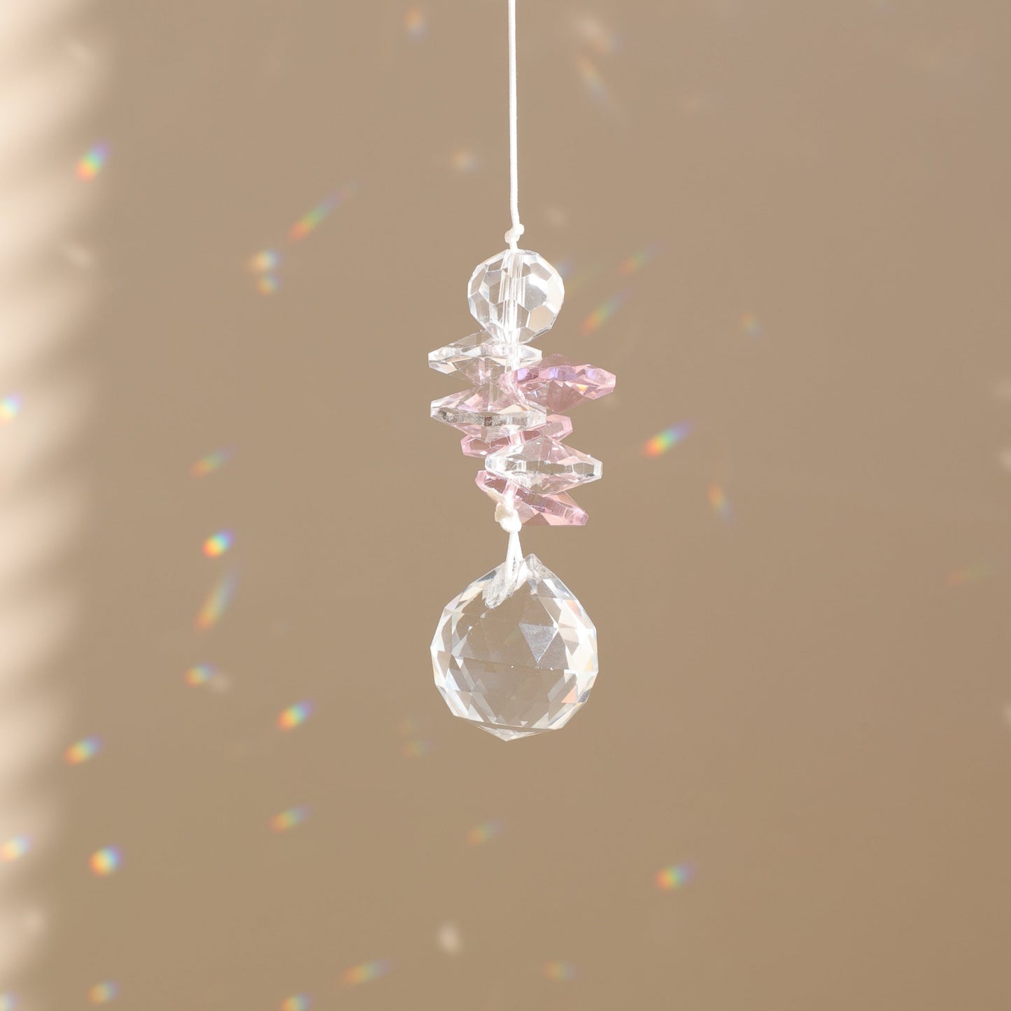 attrape-soleil en cristal rose qui reflète des prismes arc-en-ciel