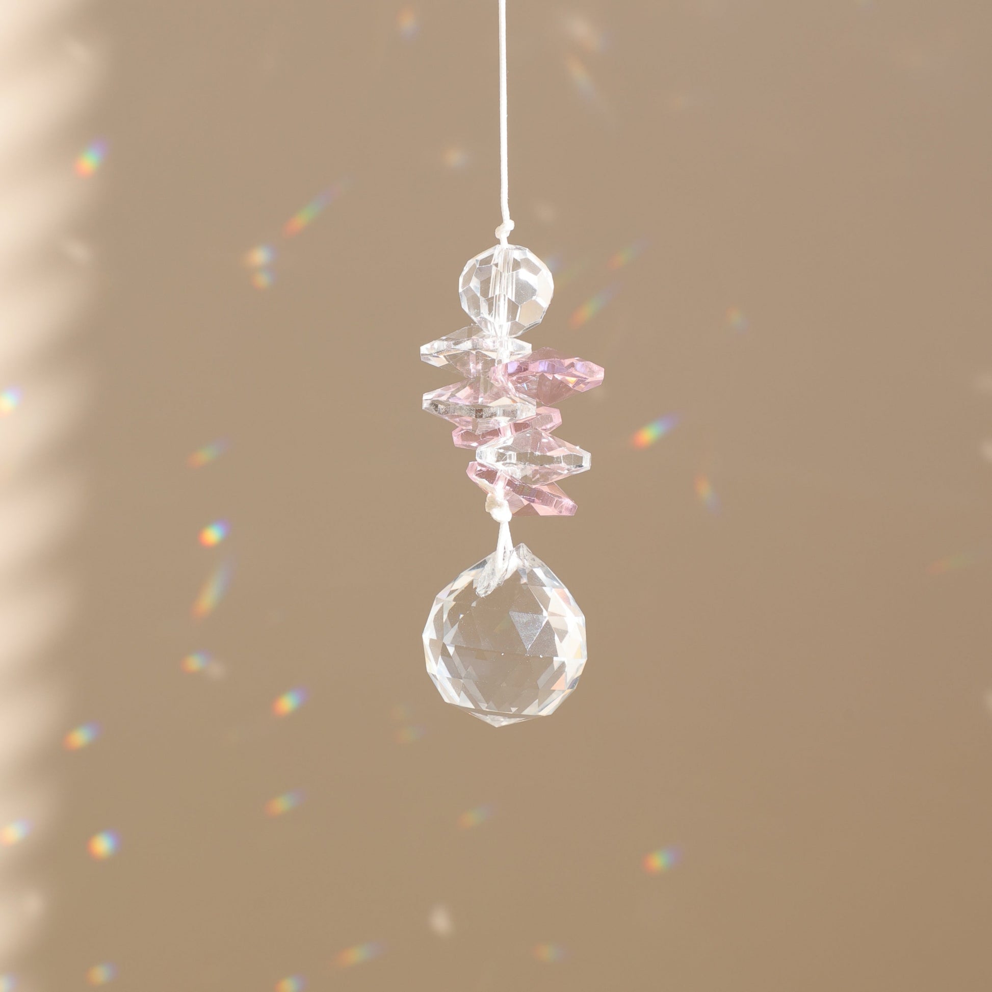 attrape-soleil en cristal rose qui reflète des prismes arc-en-ciel