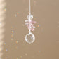 attrape-soleil en cristal rose qui reflète des prismes arc-en-ciel