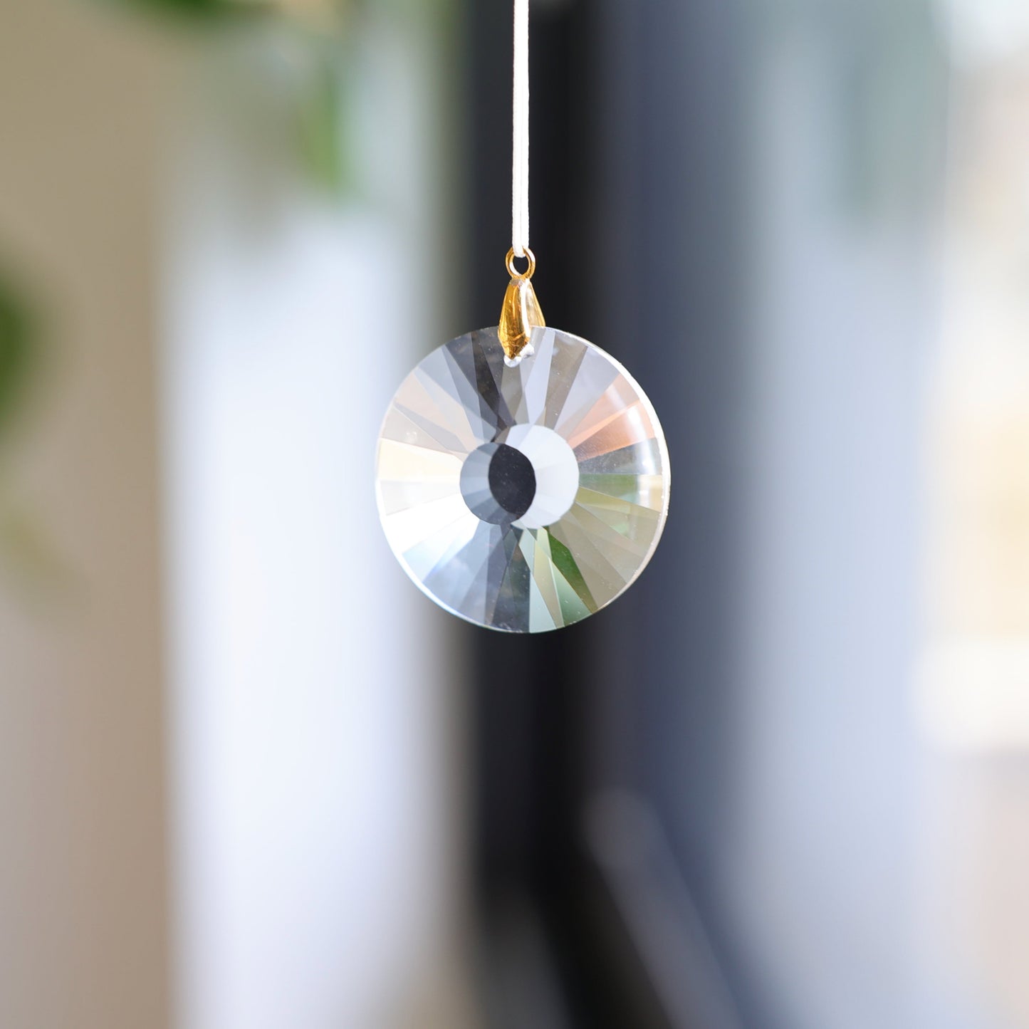 suncatcher de la marque rayonne suspendu à une fenêtre 