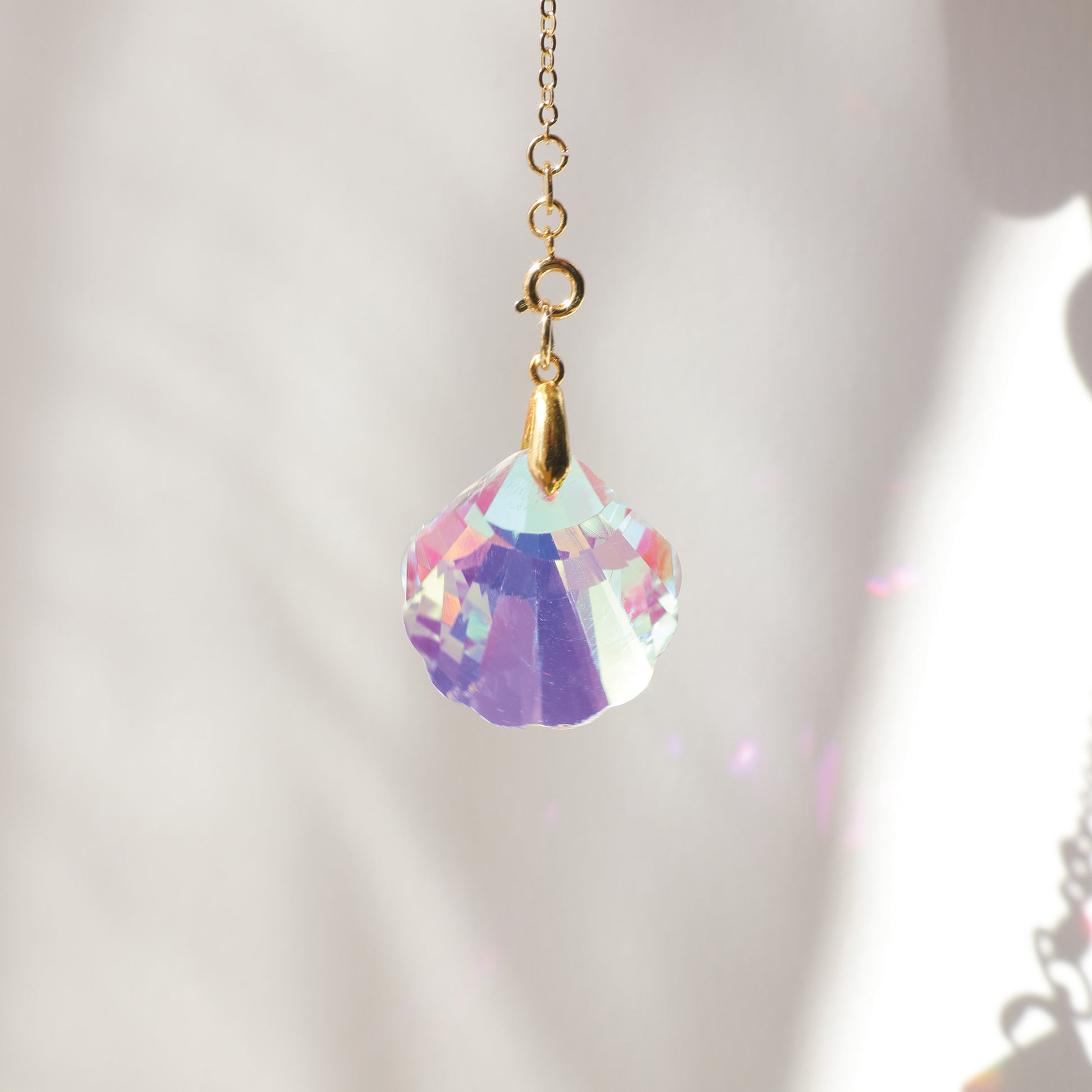 Suncatcher avec cristal en forme de coquillage, suspendu par une chaine dorée