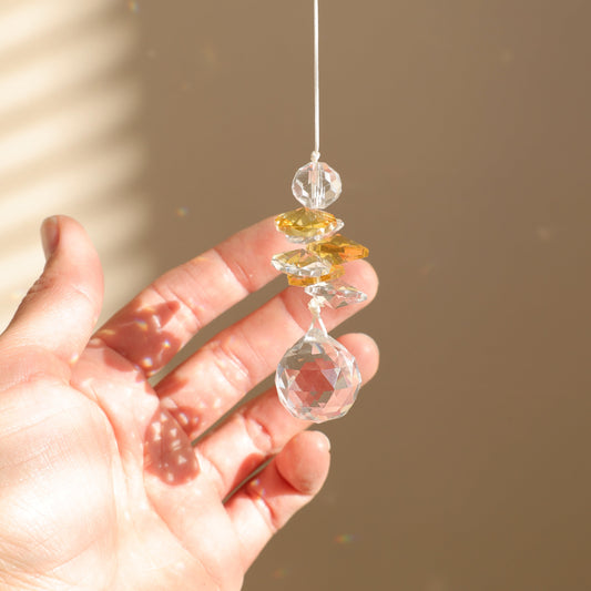 attrape-soleil en cristal tenu par une main 
