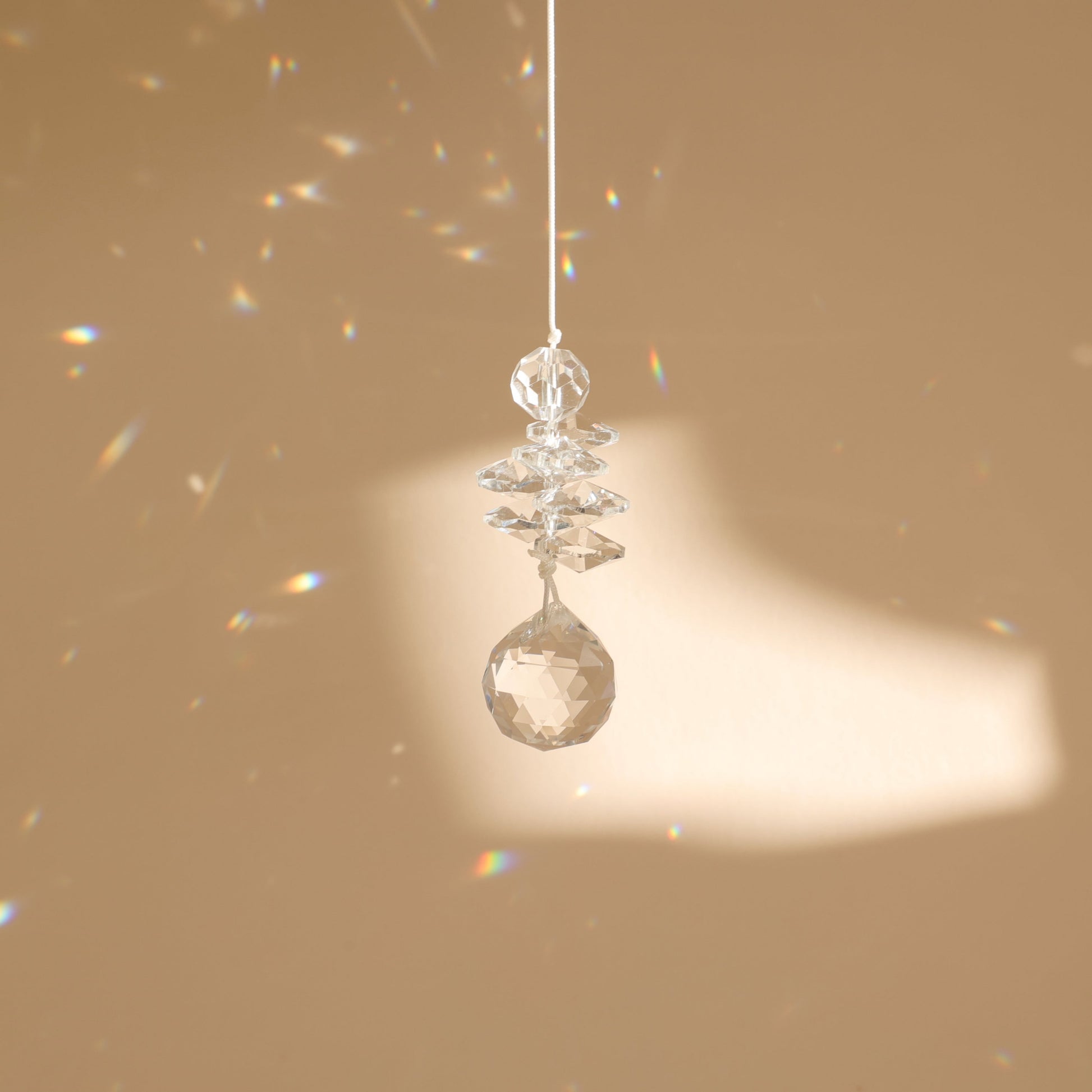 suncatcher en cristal suspendu sur un fond beige 